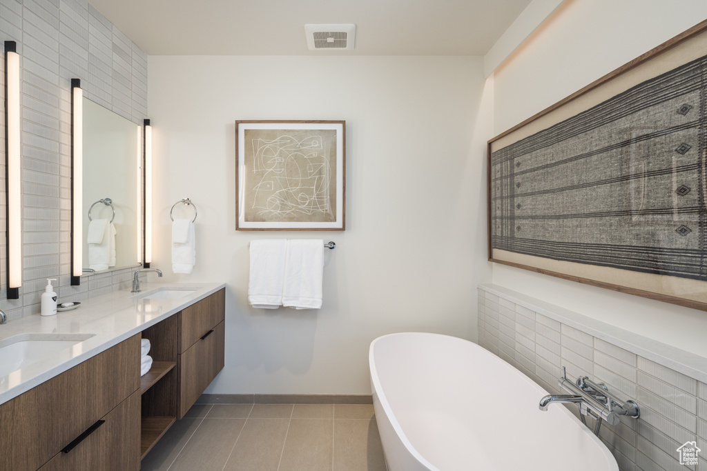 Bathroom featuring double vanity, a freestanding bath, tile patterned flooring, and backsplash