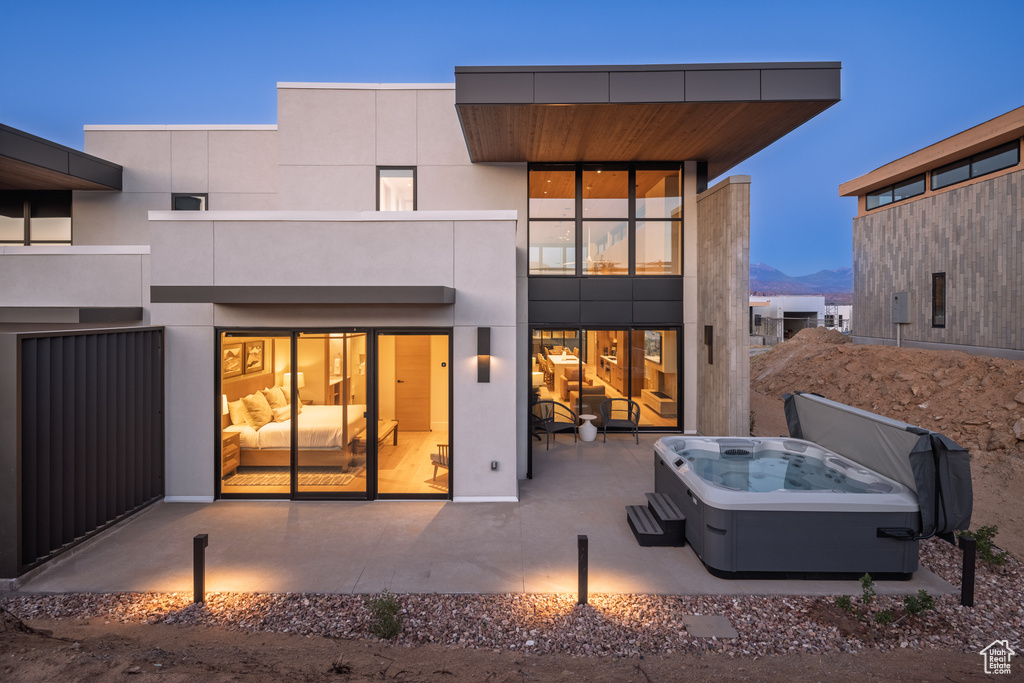 Rear view of property featuring a hot tub, a patio, and a mountain view