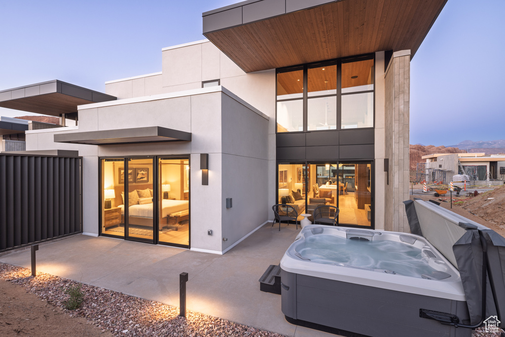 Back of house featuring a hot tub and a patio area