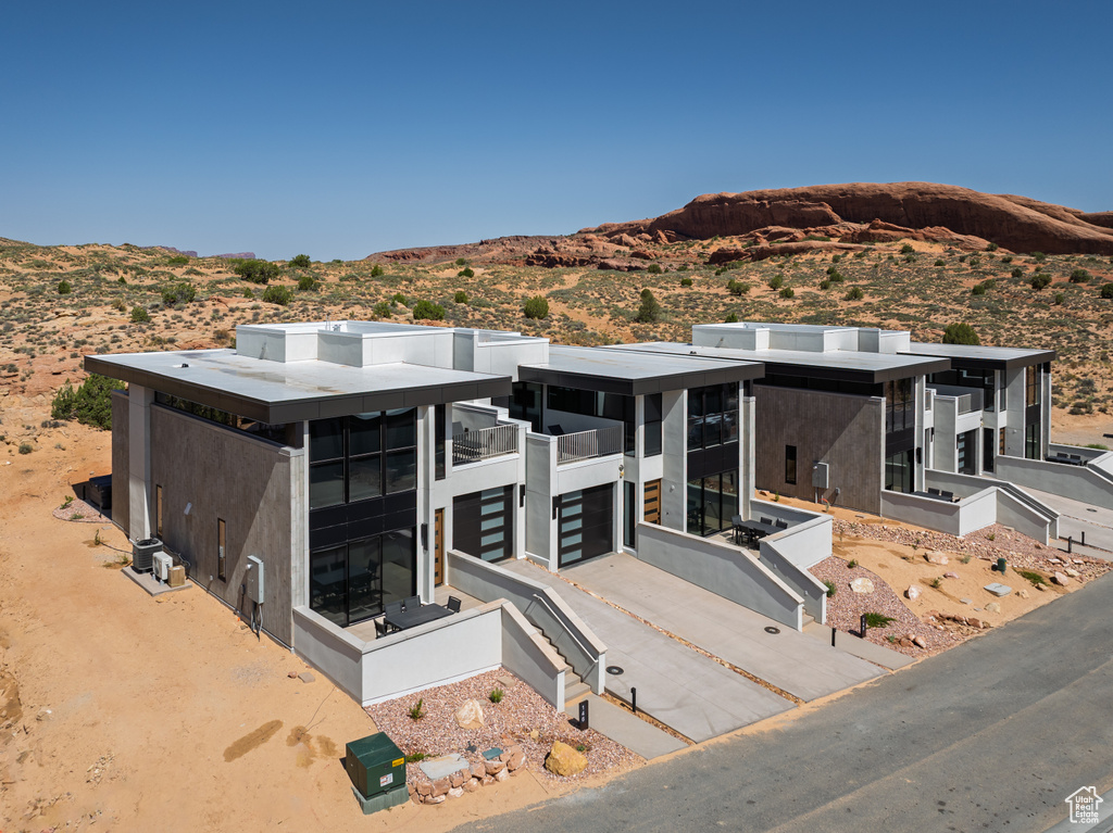 Rear view of house featuring a mountain view, stucco siding, a balcony, and a garage