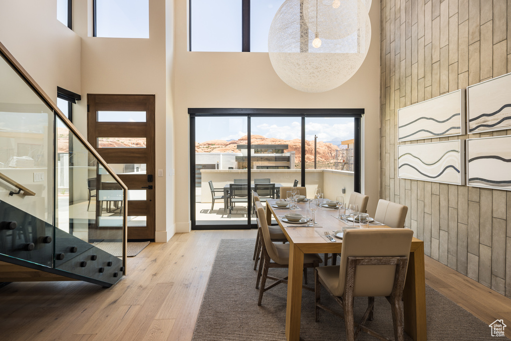 Dining area with stairway, a towering ceiling, hardwood / wood-style floors, and wooden walls