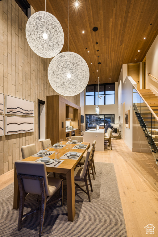 Dining room featuring wood ceiling, stairway, light wood-style flooring, a towering ceiling, and recessed lighting