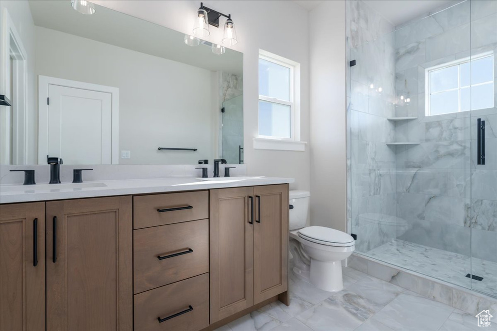 Bathroom with double vanity, a shower with door, tile floors, and plenty of natural light