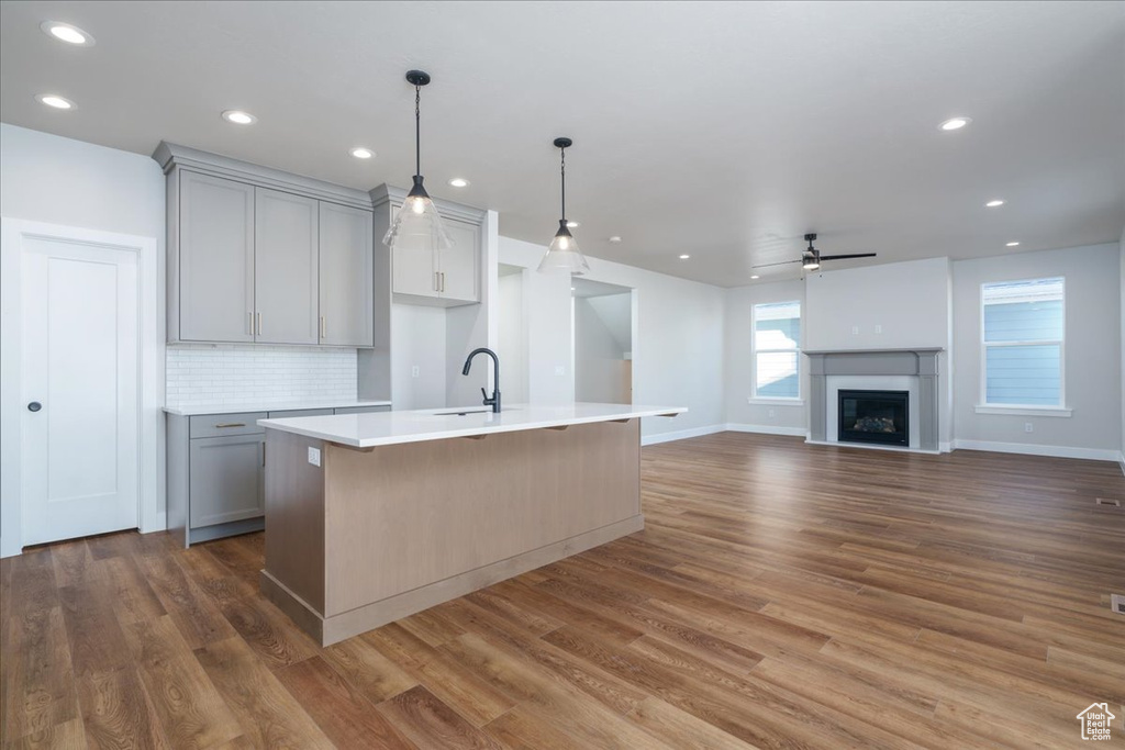 Kitchen with dark hardwood / wood-style flooring, a center island with sink, gray cabinets, and ceiling fan