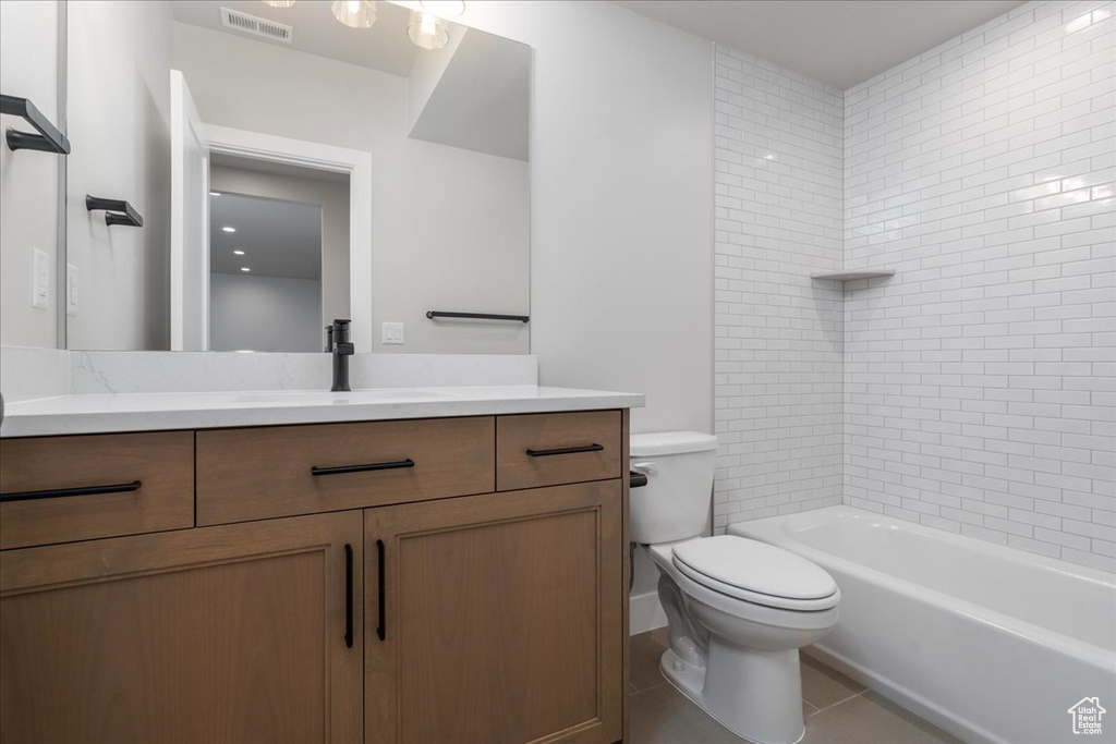 Full bathroom featuring vanity, tile flooring, tiled shower / bath combo, and toilet