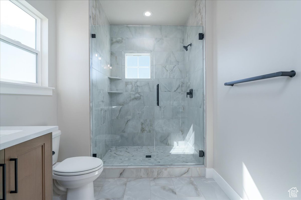 Bathroom with vanity, toilet, a shower with door, and tile flooring
