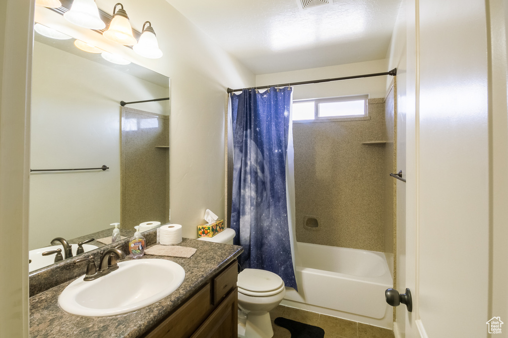 Full bathroom featuring tile floors, toilet, large vanity, and shower / tub combo with curtain