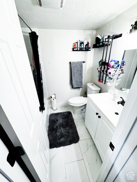 Bathroom with a textured ceiling, tile floors, large vanity, and toilet