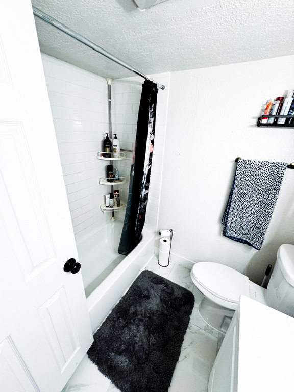 Bathroom featuring curtained shower, tile floors, a textured ceiling, and toilet