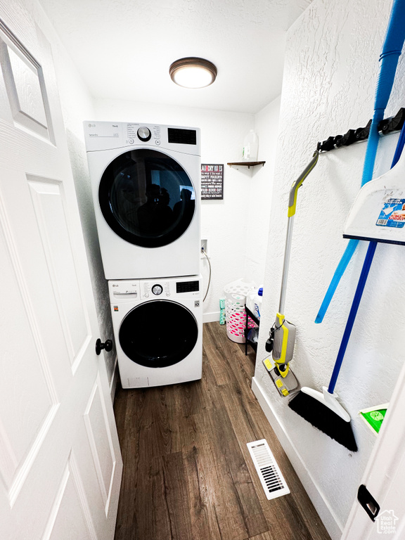 Clothes washing area featuring hookup for a washing machine, dark hardwood / wood-style flooring, and stacked washing maching and dryer