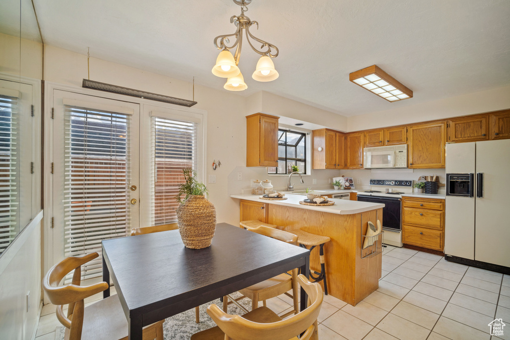 Kitchen featuring a chandelier, light tile flooring, white appliances, sink, and hanging light fixtures