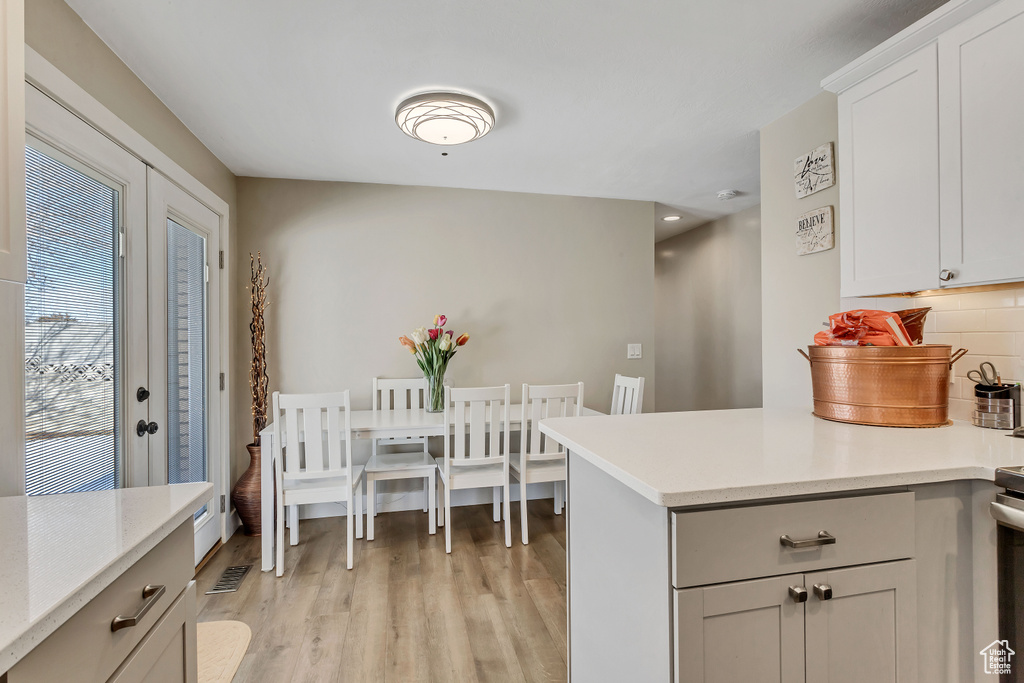 Kitchen featuring white cabinetry, backsplash, and light hardwood / wood-style floors