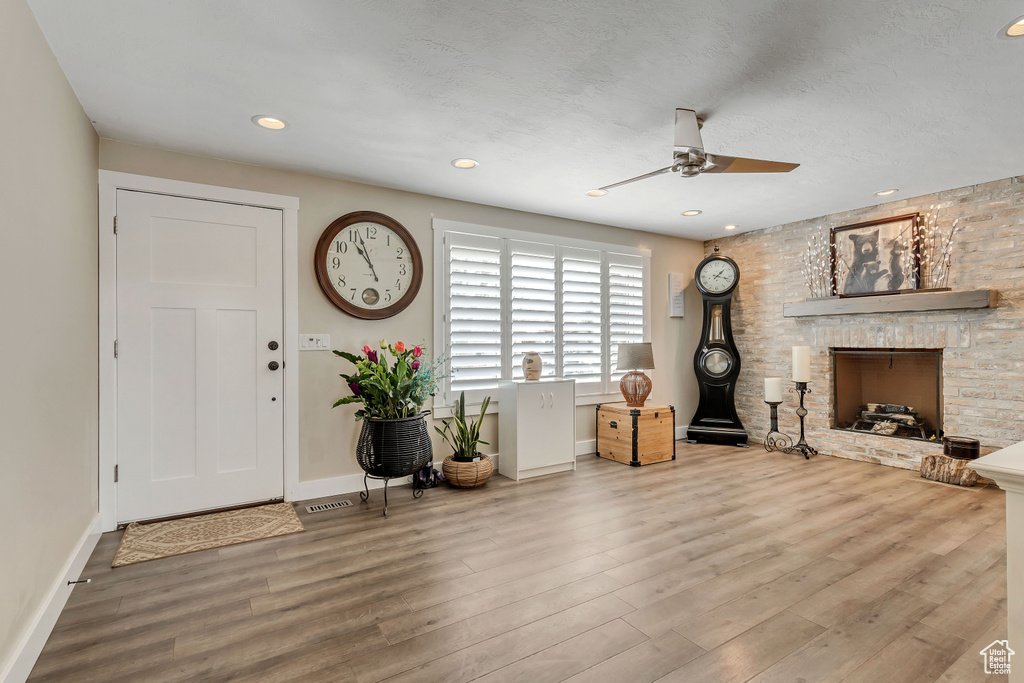 Foyer entrance featuring light hardwood / wood-style floors, ceiling fan, and a fireplace