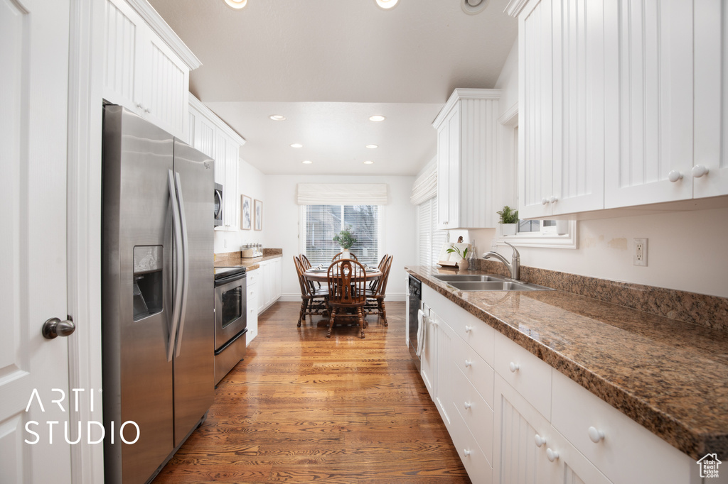 Kitchen with sink, white cabinetry, stainless steel refrigerator with ice dispenser, and light hardwood / wood-style floors