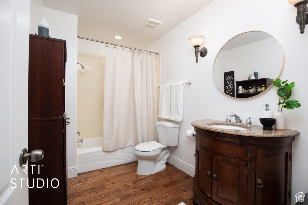 Full bathroom featuring oversized vanity, toilet, wood-type flooring, and shower / bath combo with shower curtain