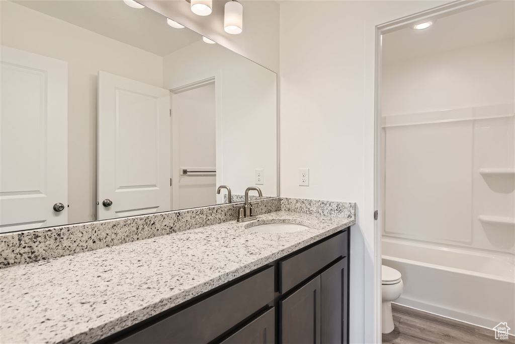 Full bathroom featuring washtub / shower combination, toilet, oversized vanity, and hardwood / wood-style flooring