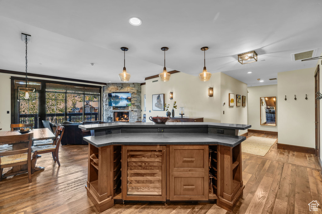 Kitchen featuring light wood-type flooring, a center island, hanging light fixtures, and beverage cooler