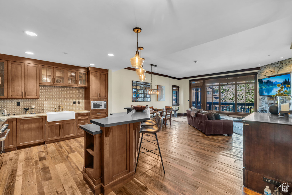 Kitchen featuring a center island, hardwood / wood-style flooring, stainless steel microwave, and decorative light fixtures