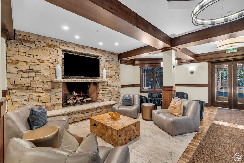 Living room with light hardwood / wood-style flooring, french doors, a stone fireplace, and beam ceiling