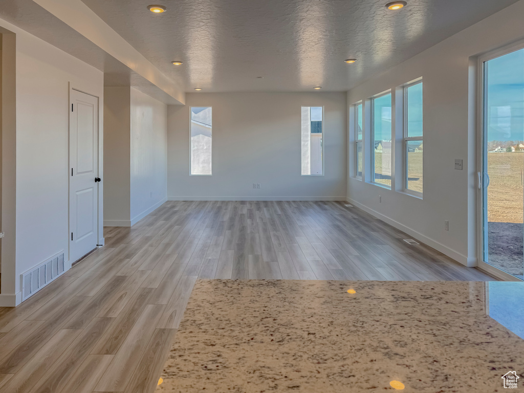 Empty room featuring a textured ceiling and light hardwood / wood-style flooring