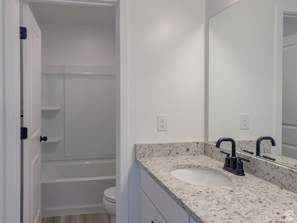 Full bathroom featuring hardwood / wood-style flooring, vanity, toilet, and shower / bathtub combination