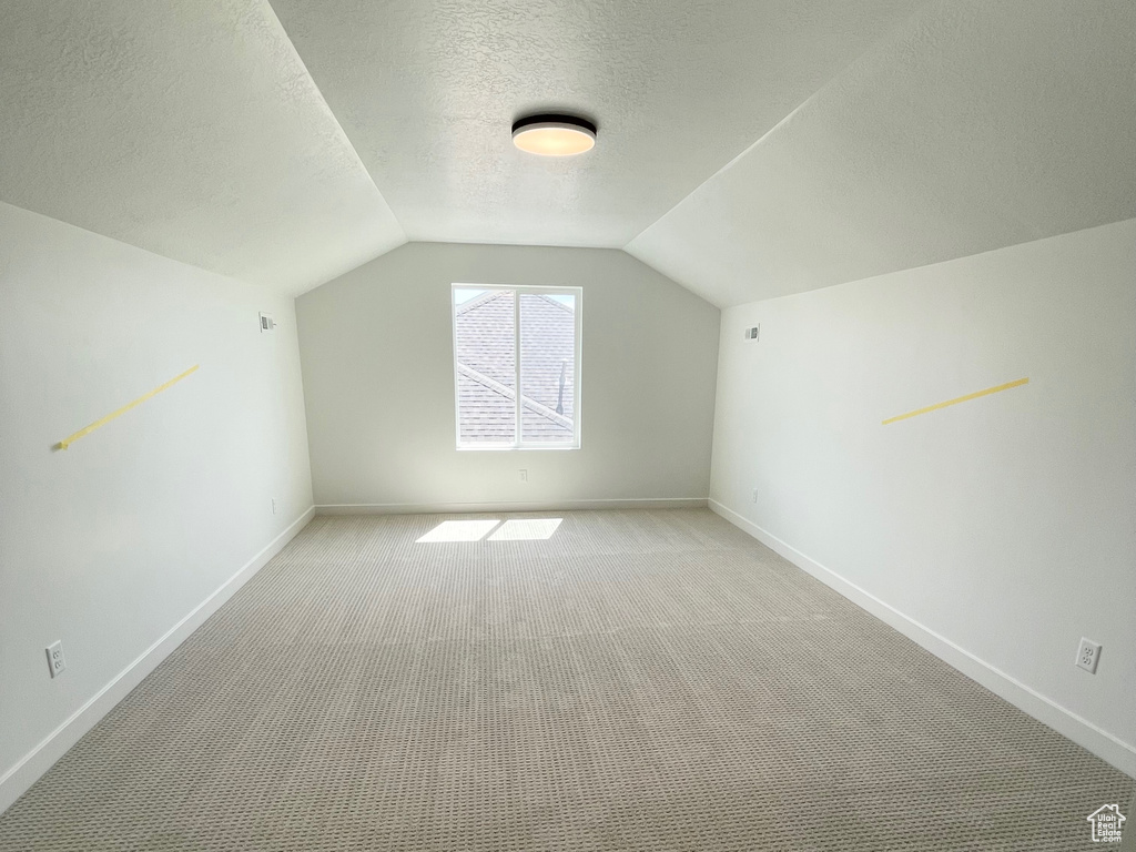 Bonus room with lofted ceiling, carpet floors, and a textured ceiling