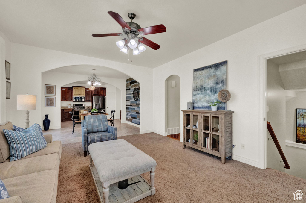 Carpeted living room with ceiling fan with notable chandelier