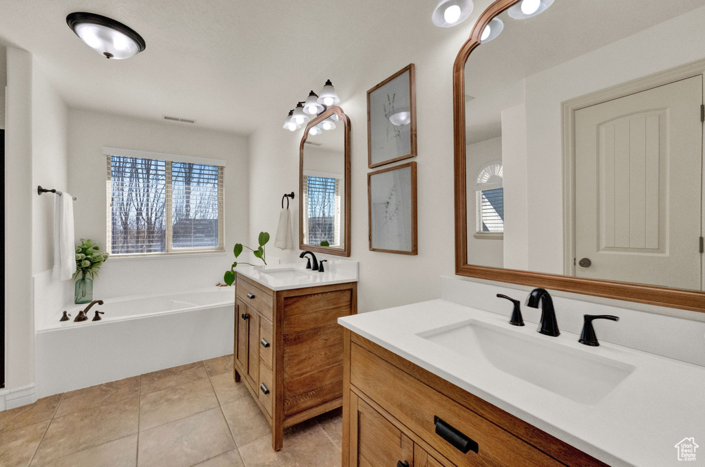Bathroom with tile flooring, a bath, and double sink vanity