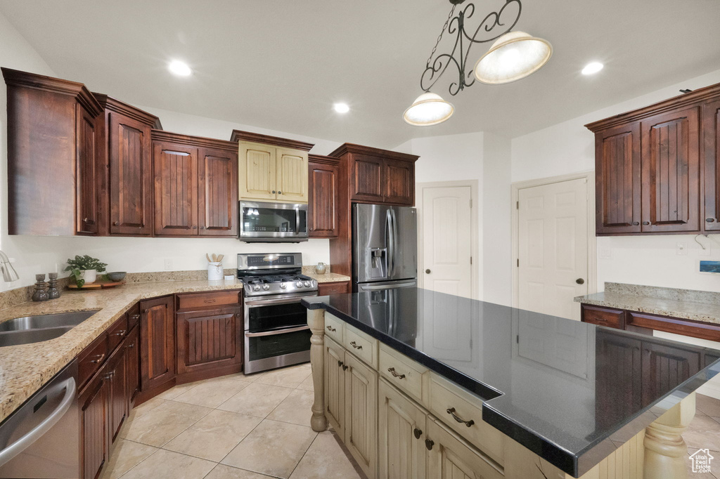 Kitchen featuring a kitchen island, light tile flooring, sink, pendant lighting, and stainless steel appliances