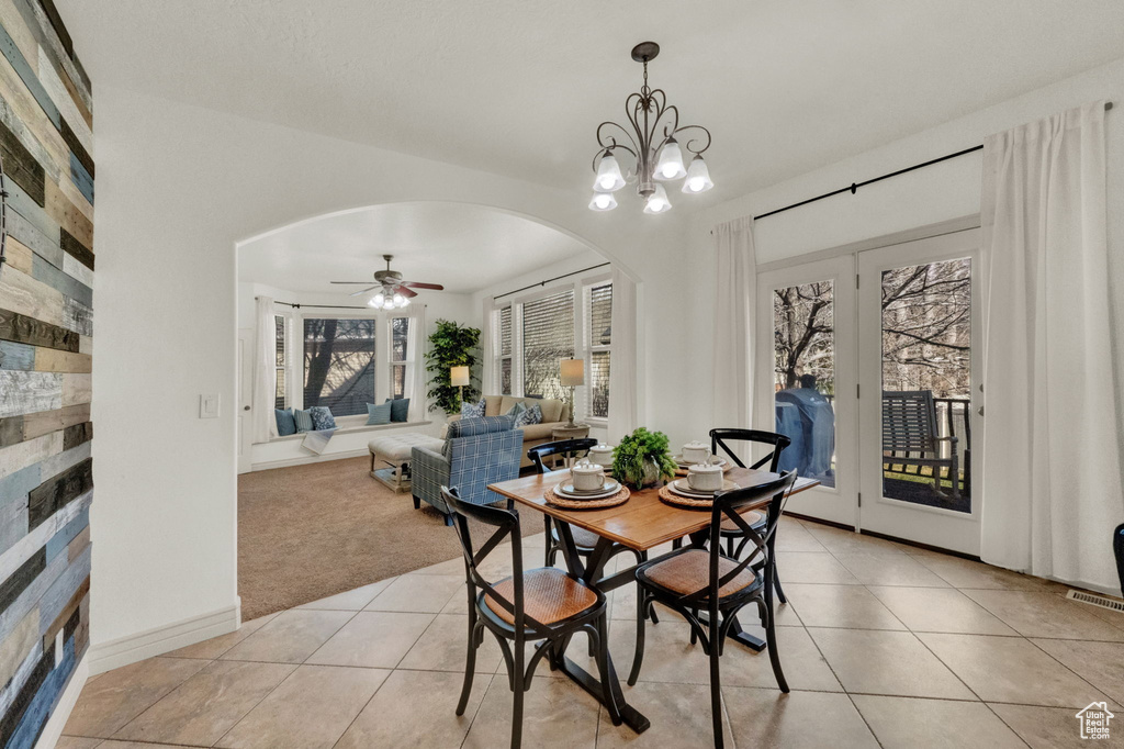 Dining area with light tile flooring and ceiling fan with notable chandelier