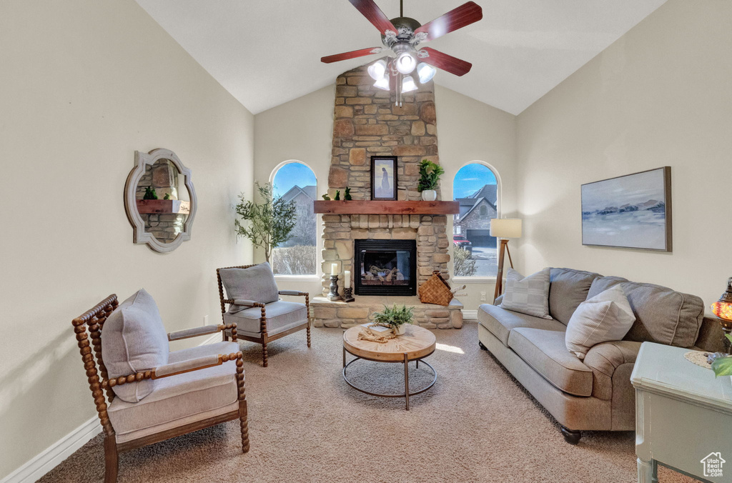 Living room featuring high vaulted ceiling, a fireplace, light carpet, and ceiling fan