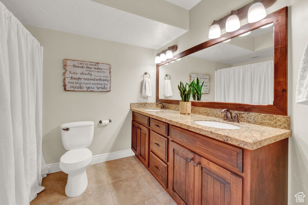 Bathroom featuring double sink, oversized vanity, tile floors, and toilet