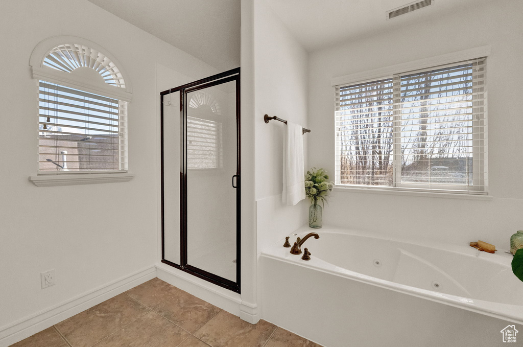 Bathroom with a wealth of natural light, independent shower and bath, and tile floors