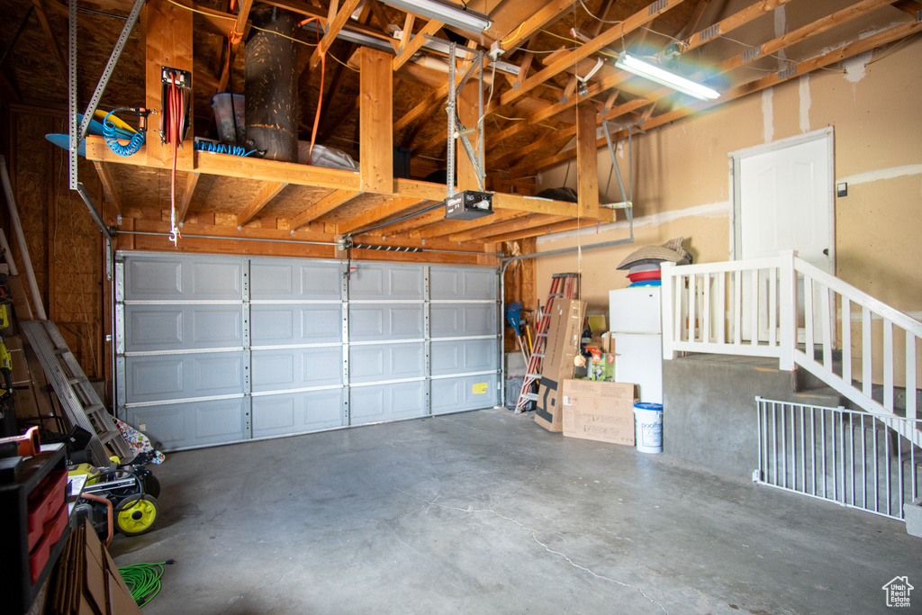 Garage featuring a garage door opener and white fridge