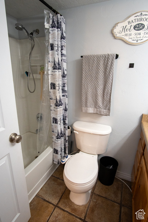 Full bathroom featuring a textured ceiling, shower / tub combo, toilet, tile flooring, and vanity