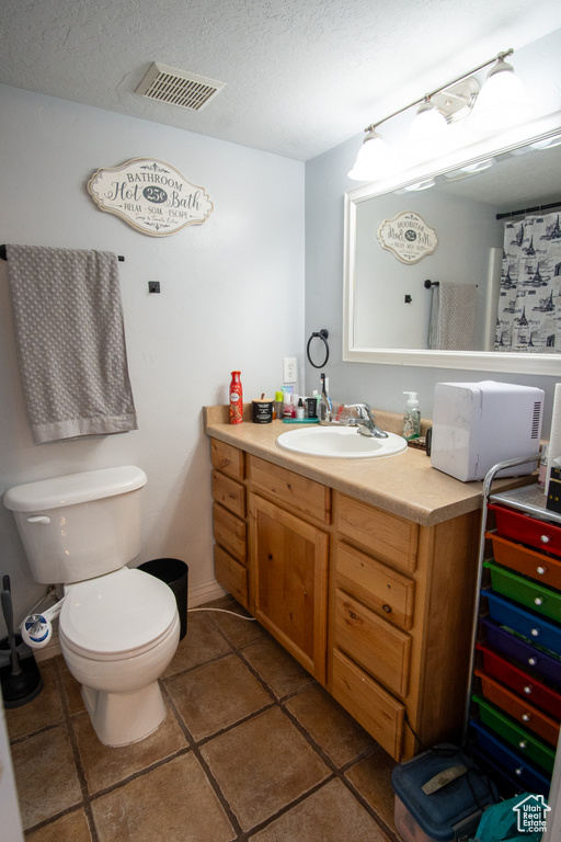 Bathroom featuring tile flooring, a textured ceiling, toilet, and vanity