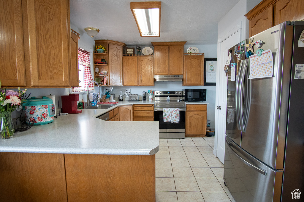 Kitchen featuring sink, kitchen peninsula, stainless steel appliances, and light tile floors