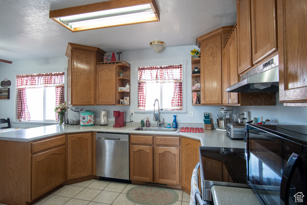 Kitchen with stainless steel dishwasher, light tile floors, and sink