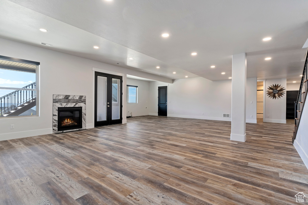 Unfurnished living room featuring plenty of natural light, dark hardwood / wood-style floors, and a high end fireplace