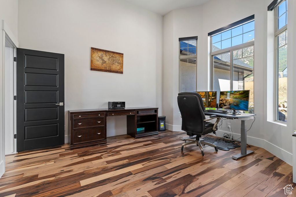 Home office featuring a high ceiling and light hardwood / wood-style flooring