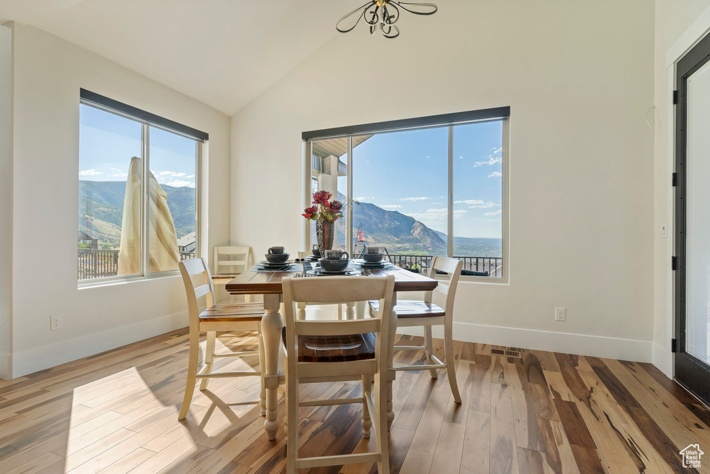 Dining area with a wealth of natural light, a mountain view, light hardwood / wood-style floors, and vaulted ceiling