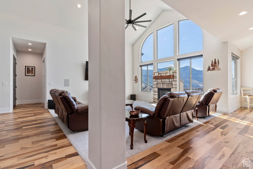 Living room with ceiling fan, high vaulted ceiling, light hardwood / wood-style floors, a mountain view, and a fireplace