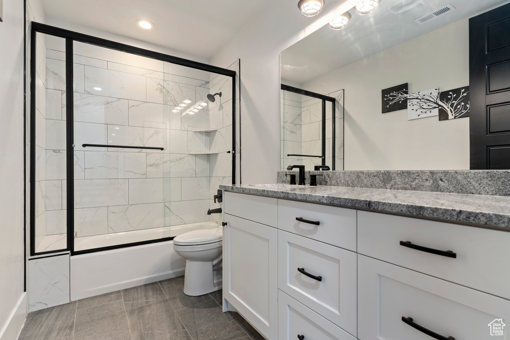 Full bathroom featuring combined bath / shower with glass door, toilet, tile flooring, and oversized vanity