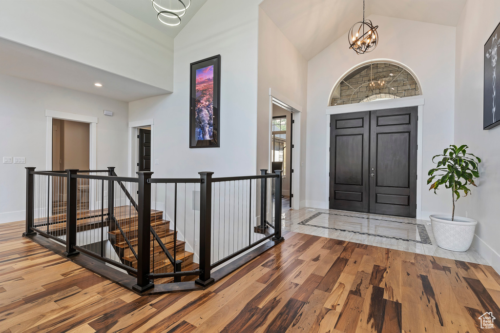 Entrance foyer featuring an inviting chandelier, high vaulted ceiling, and hardwood / wood-style floors