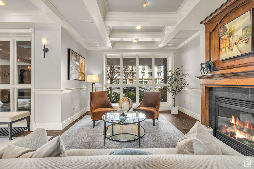 Living room featuring a tiled fireplace, dark hardwood / wood-style flooring, ornamental molding, coffered ceiling, and beamed ceiling