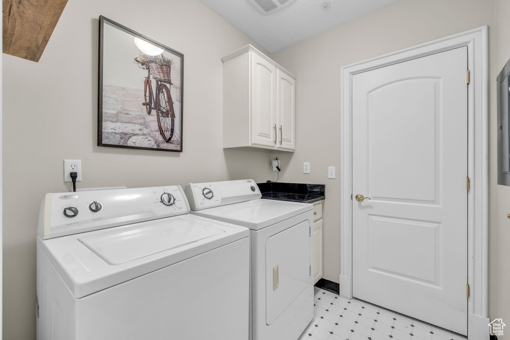 Laundry room featuring light tile floors, separate washer and dryer, and cabinets