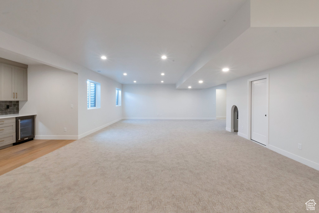 Basement with wine cooler and light colored carpet