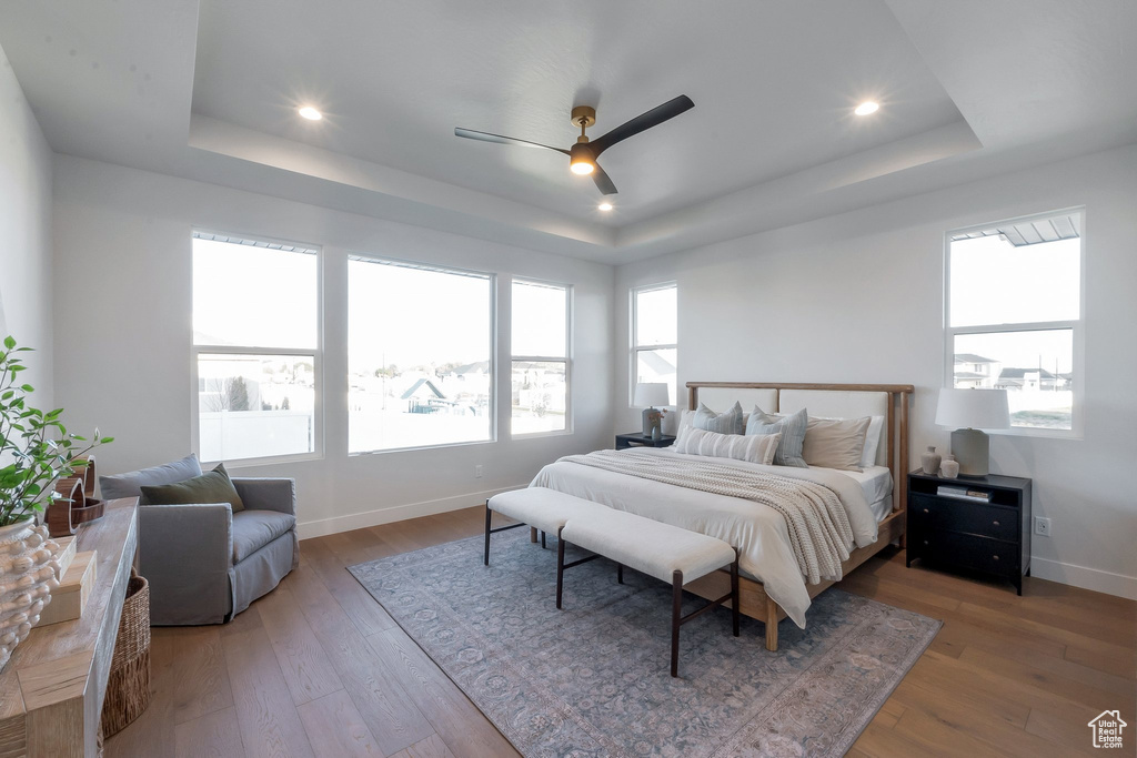 Bedroom featuring ceiling fan, a raised ceiling, and wood-type flooring