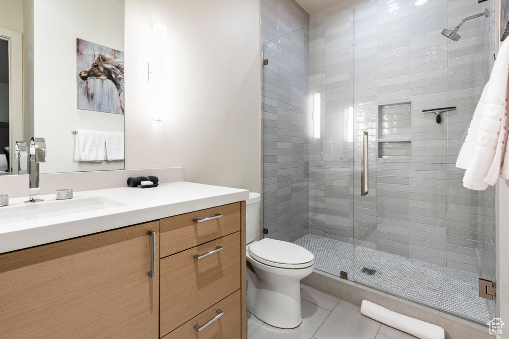 Bathroom with a shower with door, vanity, tile patterned flooring, and toilet