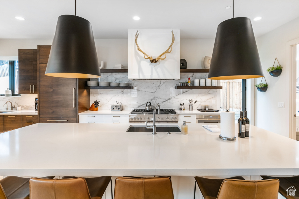 Kitchen with decorative light fixtures, decorative backsplash, and a kitchen breakfast bar
